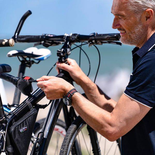 Mann montiert Fiamma Bike Block Pro S Deep Black an E-Bike auf Fahrradträger; passend für runde und ovale Rahmen von 25–100 mm.